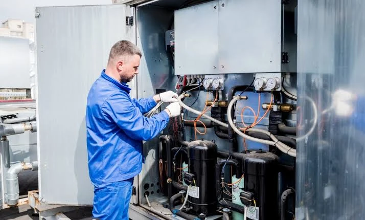 Technician servicing the internal components of a large HVAC cabinet