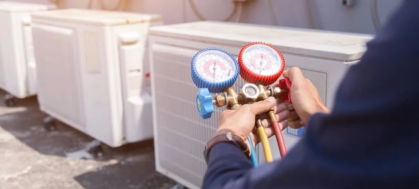 Technician checking refrigerant pressure with manifold gauges