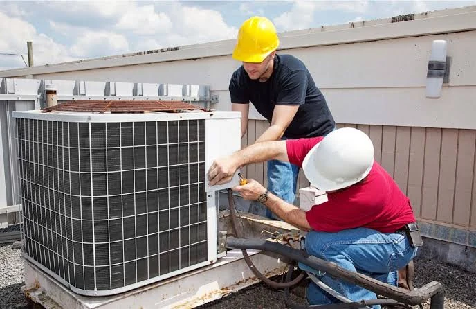 Two technicians servicing a rooftop air conditioning unit