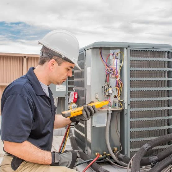 Technician using a meter to diagnose an outdoor HVAC unit